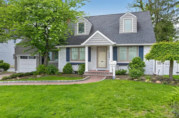 a front view of a house with a yard and potted plants