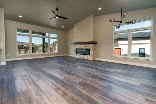 an empty room with wooden floor fireplace and windows