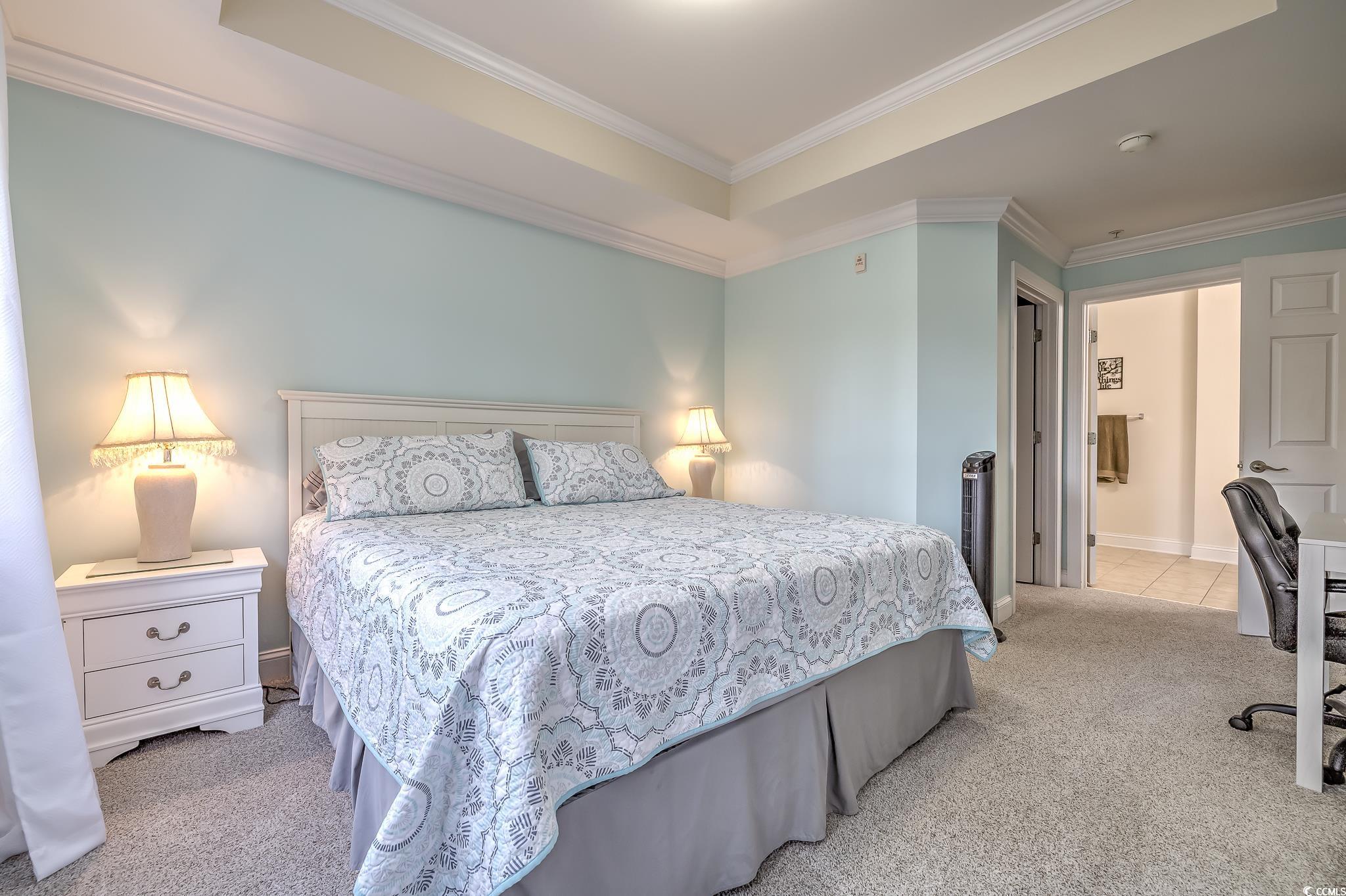 719 Shearwater Court, Unit 303 Murrells Inlet, SC 29576 - Photo 19 of 20 Bedroom featuring light colored carpet, connected bathroom, ornamental molding, a desk, and a raised ceiling