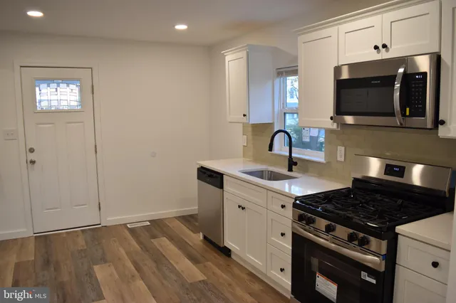 a kitchen with granite countertop a sink cabinets and stainless steel appliances