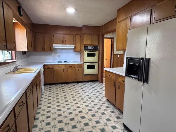 a kitchen with stainless steel appliances granite countertop a refrigerator a stove and a sink