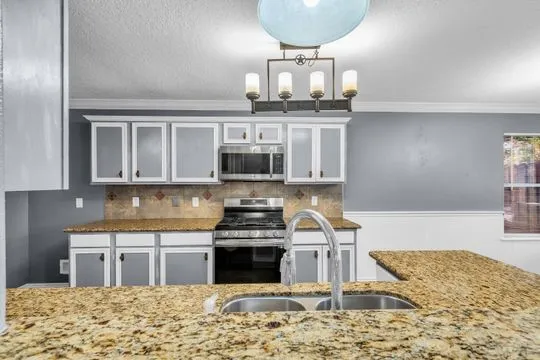 a kitchen with stainless steel appliances granite countertop a stove top oven a sink and cabinets