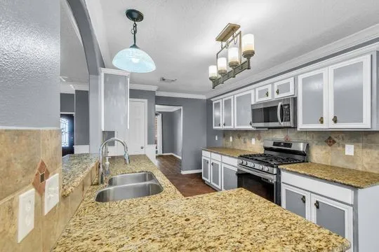 a kitchen with stainless steel appliances granite countertop a oven a stove a sink dishwasher and white cabinets with wooden floor