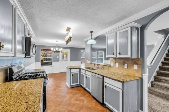 a kitchen with stainless steel appliances granite countertop a sink stove and refrigerator