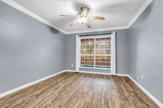 a view of an empty room with wooden floor and a window