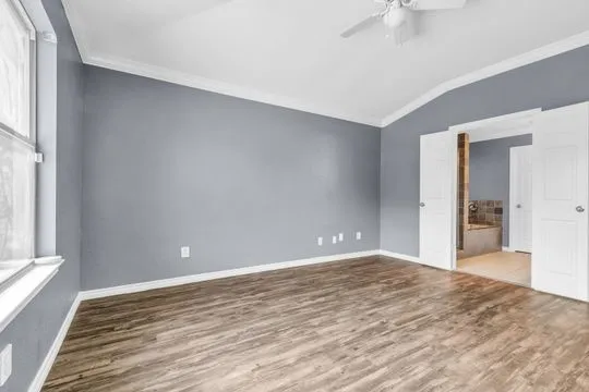 a view of an empty room with wooden floor and a window