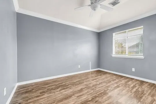 a view of empty room with wooden floor and fan