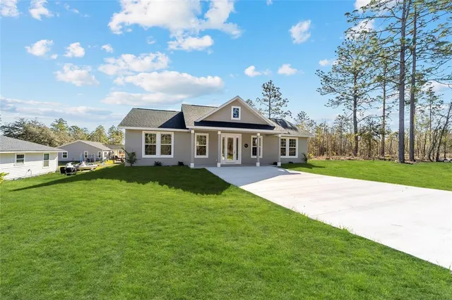 a view of a house with a big yard plants and large trees