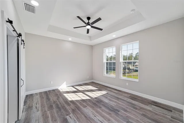 a view of empty room with wooden floor and fan