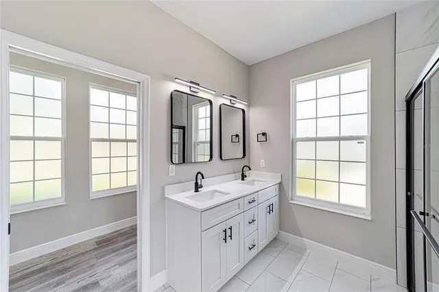 a bathroom with double vanity and a mirror