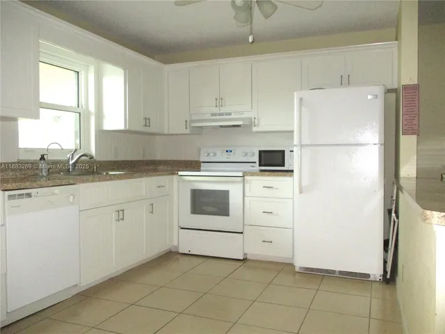 a kitchen with white cabinets and white appliances
