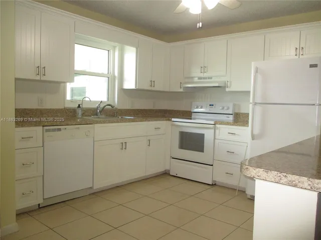 a kitchen with cabinets appliances a sink and a window