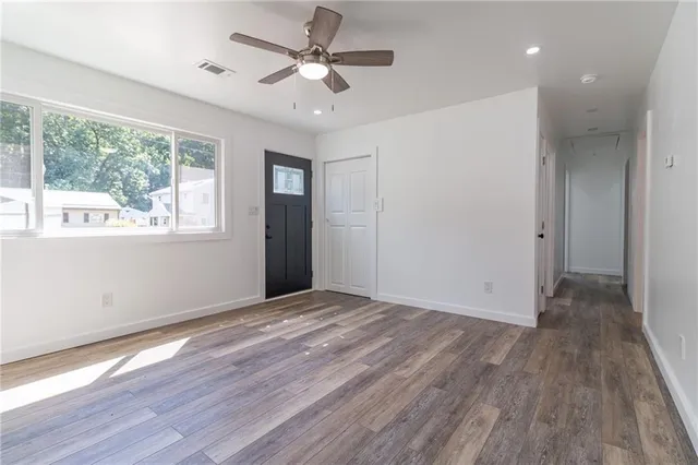 a view of empty room with wooden floor and fan