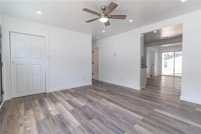 an empty room with wooden floor and a ceiling fan