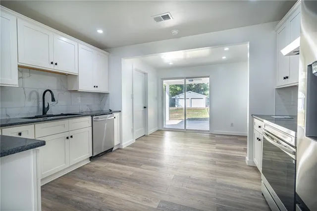 a kitchen with granite countertop white cabinets and stainless steel appliances