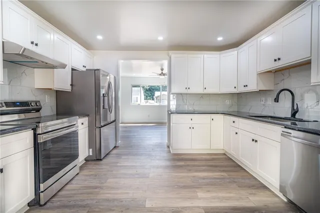 a kitchen with granite countertop a refrigerator and a stove top oven