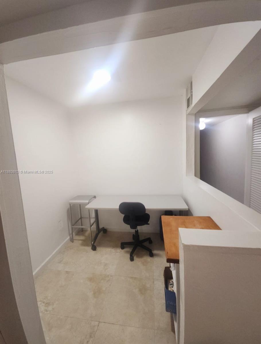 11960 Northeast 19th Drive, Unit 10 North Miami, FL 33181 - Photo 39 of 40 a room with a chair and white walls