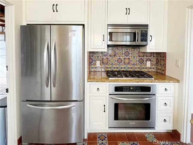 a kitchen with stainless steel appliances white cabinets a microwave and a refrigerator