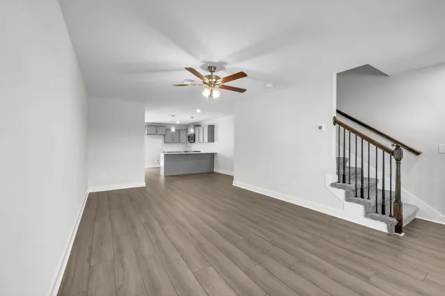 an empty room with wooden floor and a ceiling fan