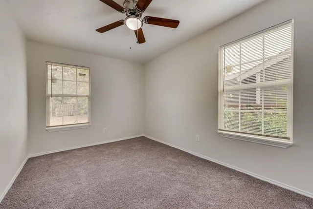 an empty room with a window and a ceiling fan