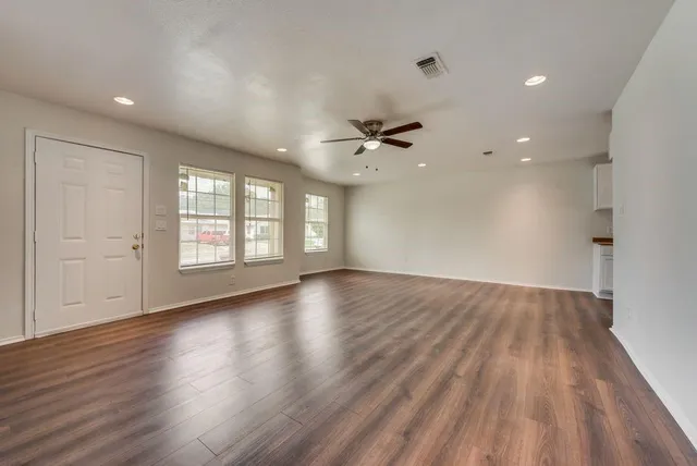 a view of an empty room with a window and wooden floor