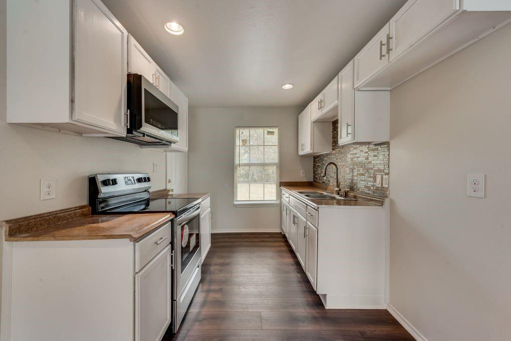 3005 Hatcher Street Fort Worth, TX 76105 - Photo 7 of 19 a kitchen with stainless steel appliances granite countertop a stove a sink and a microwave