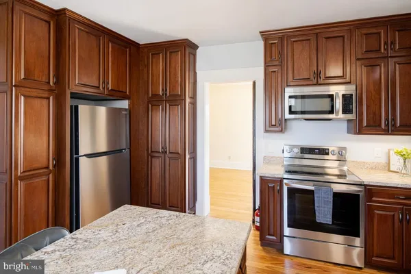 a kitchen with granite countertop a refrigerator stove and microwave