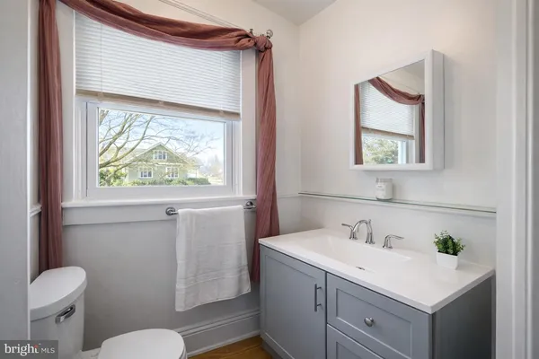 a bathroom with a sink a mirror a toilet and a window