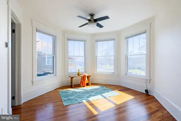 a living room with hardwood floor windows and a ceiling fan