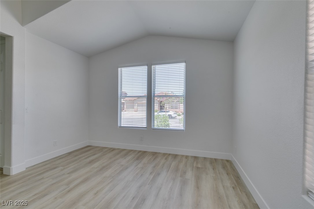 823 Wintersweet Road Henderson, NV 89015 - Photo 11 of 50 Spare room with light wood-style flooring, vaulted ceiling, and a view of city