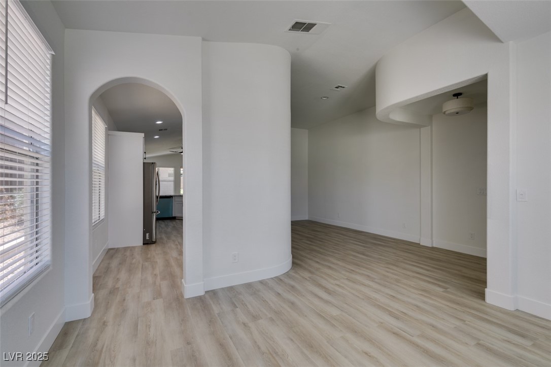 823 Wintersweet Road Henderson, NV 89015 - Photo 13 of 50 Empty room featuring arched walkways, light wood-style flooring, and recessed lighting