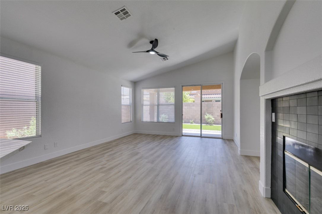 823 Wintersweet Road Henderson, NV 89015 - Photo 16 of 50 Unfurnished living room featuring lofted ceiling, light wood-style floors, a tile fireplace, and a ceiling fan