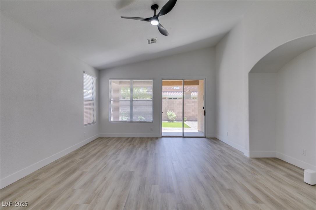 823 Wintersweet Road Henderson, NV 89015 - Photo 18 of 50 Unfurnished living room with ceiling fan, light wood finished floors, vaulted ceiling, and arched walkways