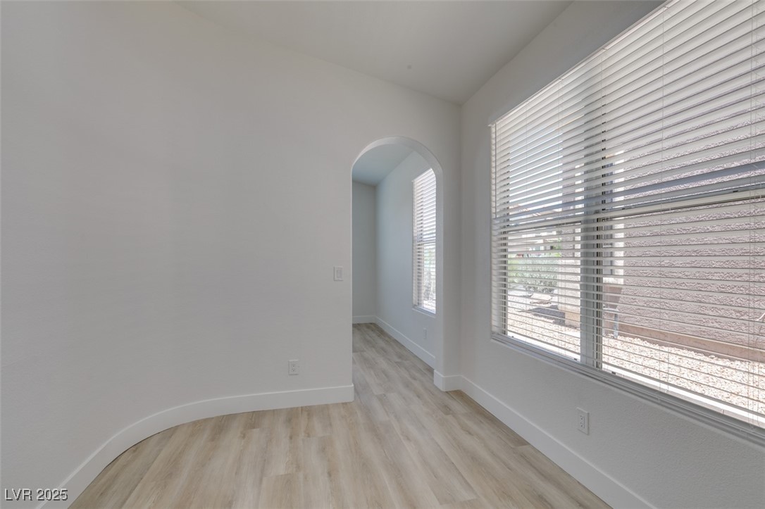 823 Wintersweet Road Henderson, NV 89015 - Photo 30 of 50 Empty room with arched walkways and light wood finished floors
