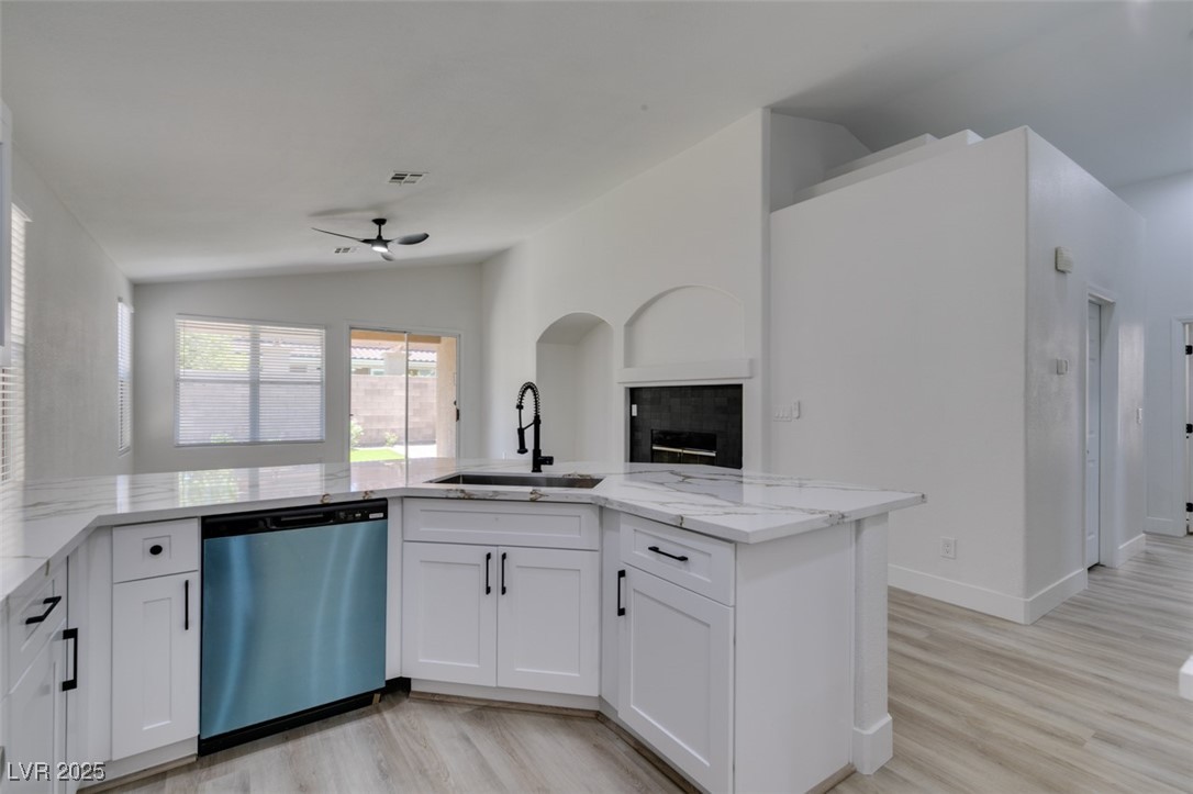 823 Wintersweet Road Henderson, NV 89015 - Photo 50 of 50 Kitchen with lofted ceiling, open floor plan, stainless steel dishwasher, light stone countertops, and light wood-style floors