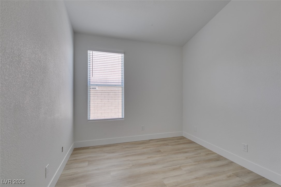 823 Wintersweet Road Henderson, NV 89015 - Photo 33 of 50 Empty room with light wood-style floors and a textured wall