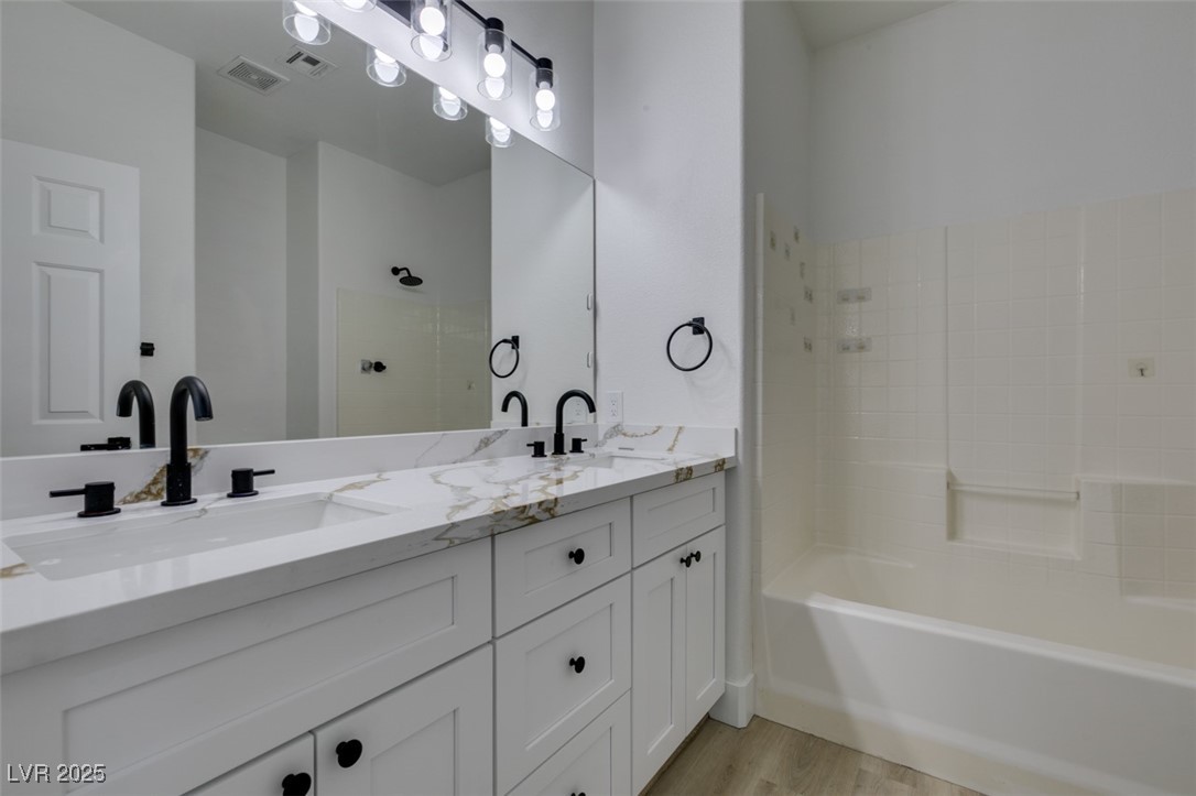 823 Wintersweet Road Henderson, NV 89015 - Photo 36 of 50 Bathroom featuring double vanity, light wood finished floors, and washtub / shower combination