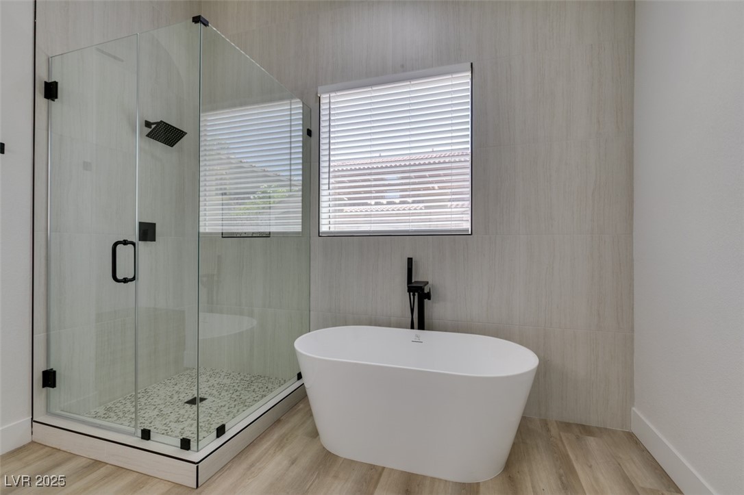 823 Wintersweet Road Henderson, NV 89015 - Photo 42 of 50 Bathroom featuring a stall shower, a freestanding tub, tile walls, and light wood finished floors