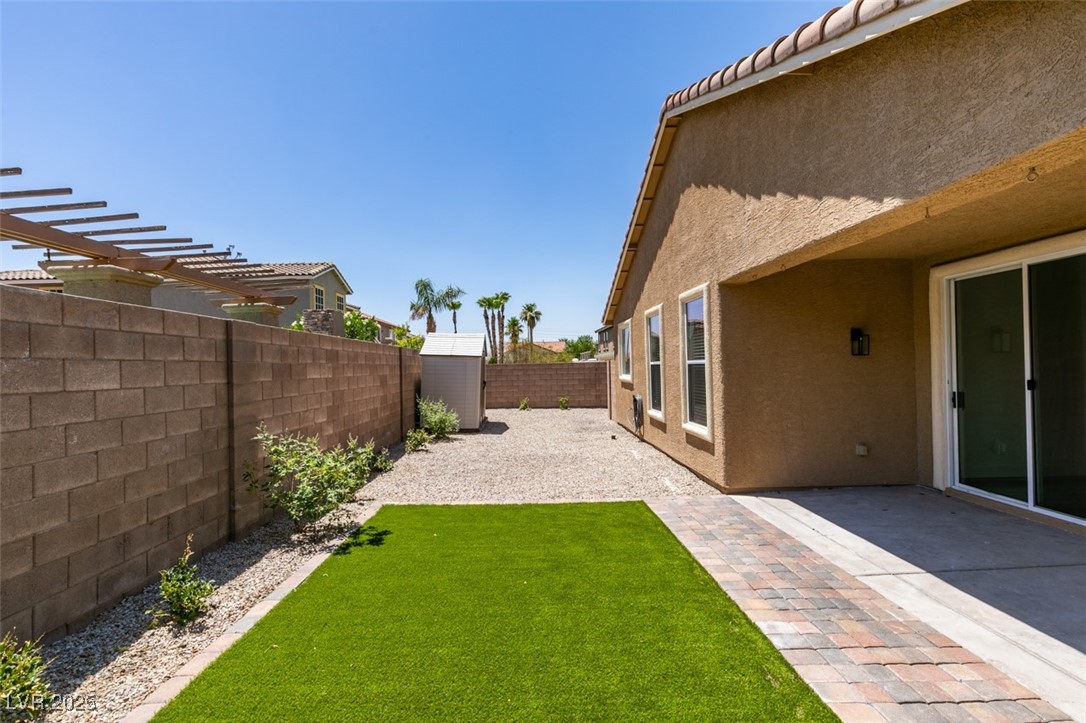 823 Wintersweet Road Henderson, NV 89015 - Photo 45 of 50 Fenced backyard featuring a storage unit, a patio area, and a pergola