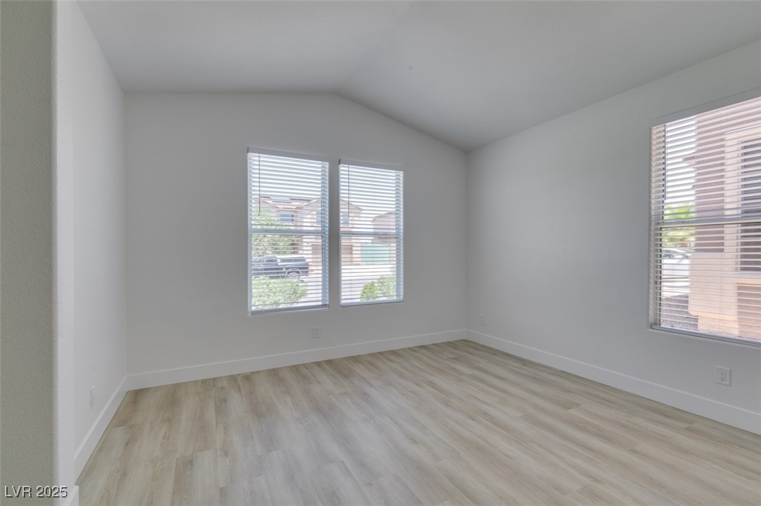 823 Wintersweet Road Henderson, NV 89015 - Photo 7 of 50 Unfurnished room featuring light wood finished floors and vaulted ceiling