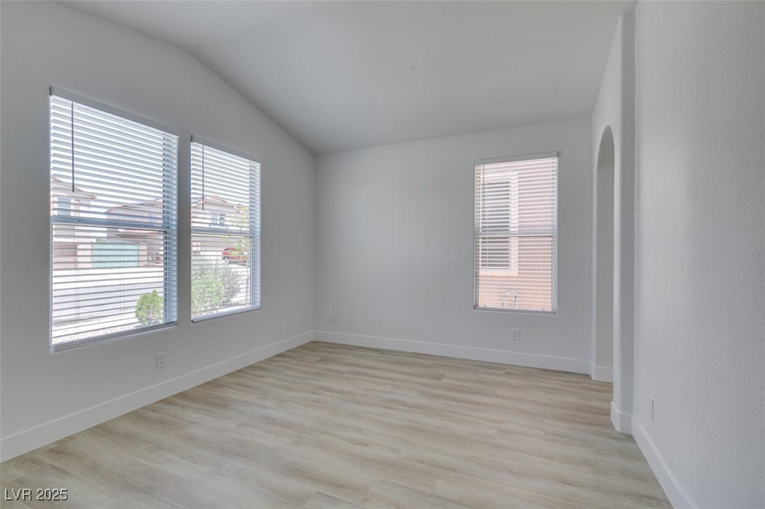823 Wintersweet Road Henderson, NV 89015 - Photo 8 of 50 Unfurnished room featuring lofted ceiling, light wood-style flooring, and arched walkways