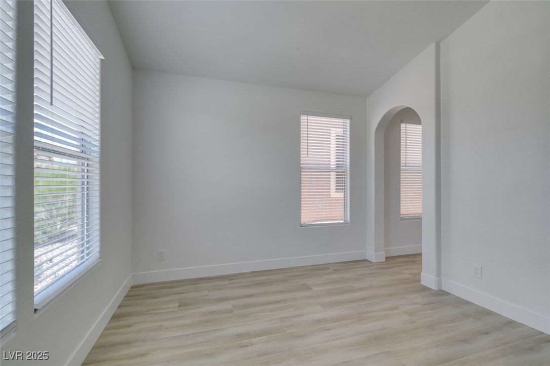 823 Wintersweet Road Henderson, NV 89015 - Photo 9 of 50 Unfurnished room featuring healthy amount of natural light, light wood-type flooring, and arched walkways
