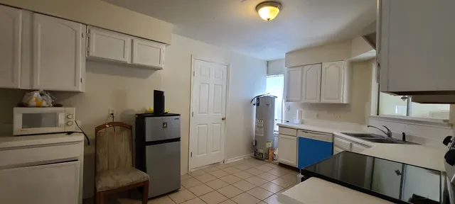 a kitchen with white cabinets and black appliances