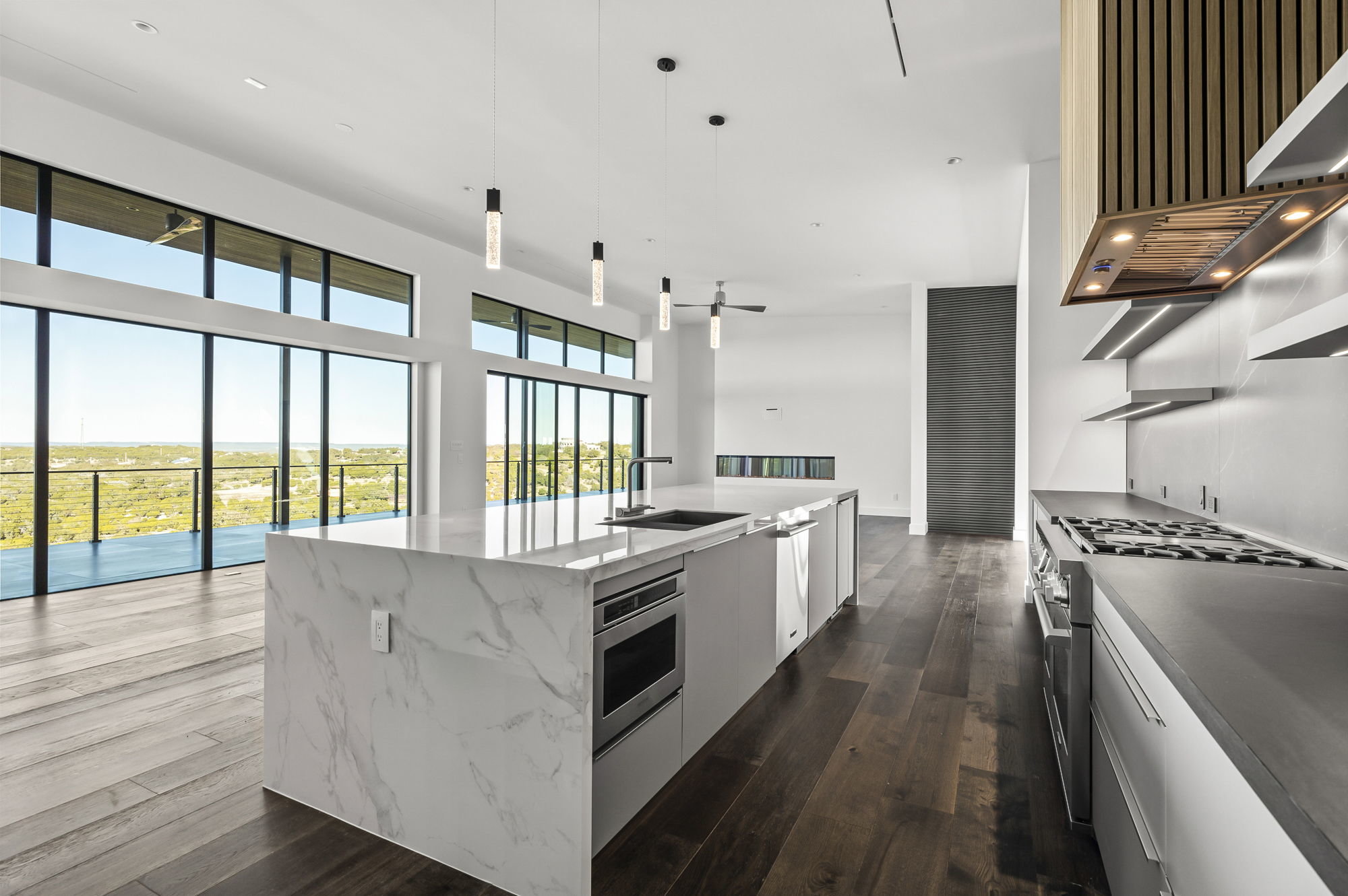 1702 Moonlight Trace Spicewood, TX 78669 - Photo 20 of 40 Kitchen featuring a large island, stainless steel appliances, white cabinets, dark wood finished floors, and light stone countertops