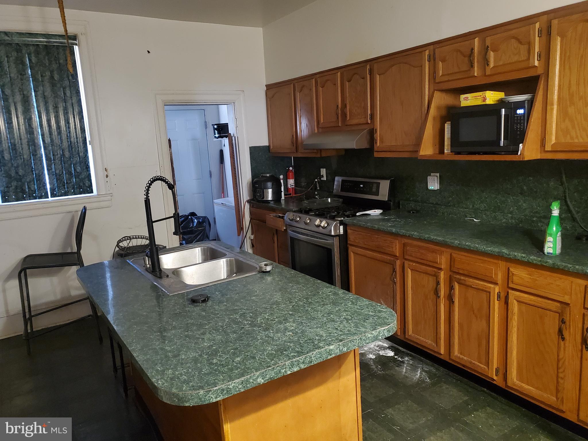 6058 Webster Street Philadelphia, PA 19143 - Photo 4 of 15 a kitchen with kitchen island granite countertop a stove top oven microwave and cabinets