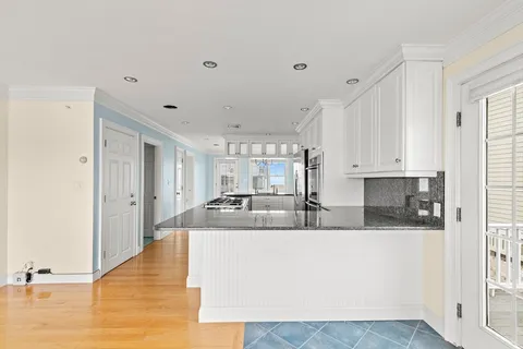 a large white kitchen with kitchen island a sink stainless steel appliances and cabinets