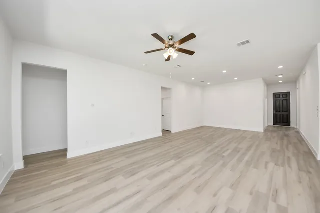 a view of empty room with wooden floor and ceiling fan