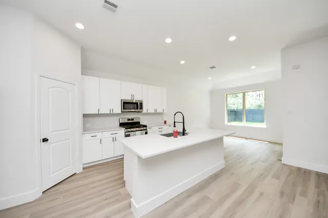 a kitchen with stainless steel appliances a sink a stove a refrigerator cabinets and a window