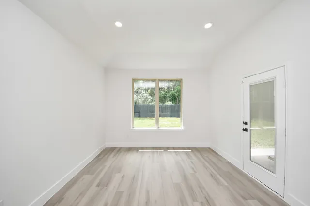 an empty room with wooden floor and windows