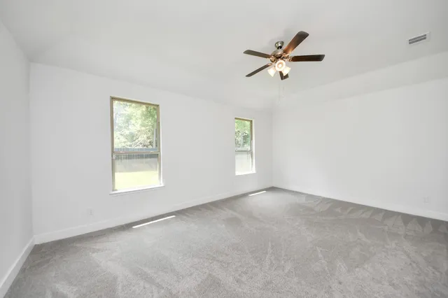 an empty room with windows and fan